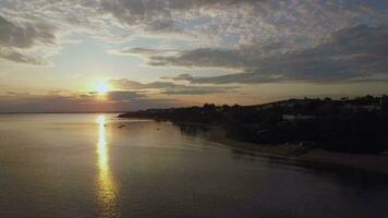 Coast with houses and golden sunset over sea, aerial Trikorfo Beach, Greece video