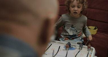 Boy playing table hockey with grandpa video