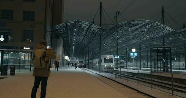 hombre tomando móvil vídeo de tren dejando estación a noche, helsinki video