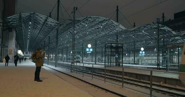 hombre haciendo móvil vídeo de tren llegando a el estación a noche helsinki video