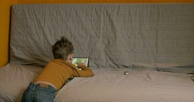 Child spending leisure with touch pad at home video