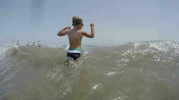 bambino bagnarsi nel il mare e salto con onda video