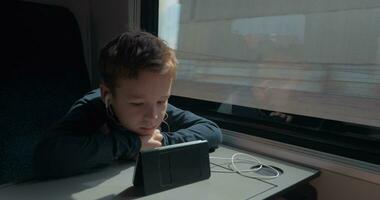 Kid with earphones watching cartoon on cell in train video