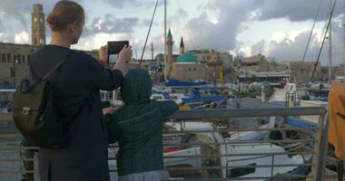 Woman with son taking photos when visiting Acre port, Israel video