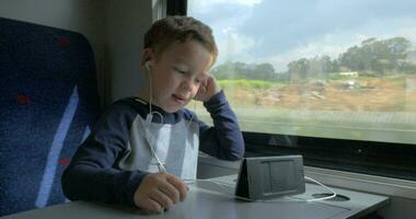 Boy video chatting in train using cell and hands free set
