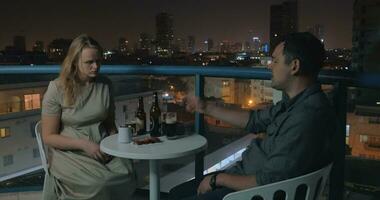 Young couple relaxing and having drinks in rooftop cafe of night Tel Aviv video