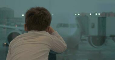 Curious boy looking at plane while waiting for the flight video