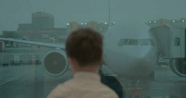 Boy looking at the plane through the airport window video
