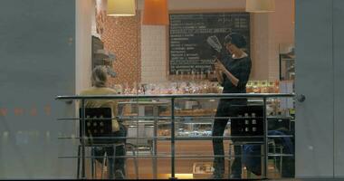 mujer con célula haciendo fotos de amigo durante el reunión en café video