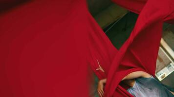 an Asian man dancing with a hanging red cloth very agile and energetic in an old building video