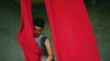 un asiático hombre bailando con un colgando rojo paño muy ágil y energético en un antiguo edificio video