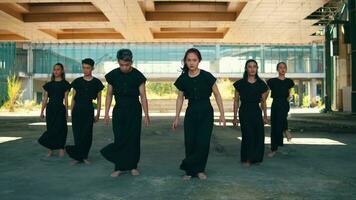 uma grupo do ásia homens dentro Preto roupas dançando com seus mãos e cheio do entusiasmo debaixo a construção video