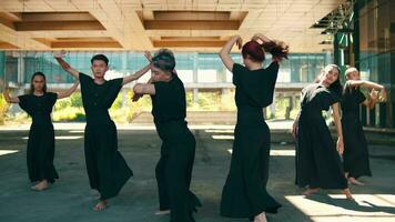 ein Gruppe von asiatisch Tänzer tanzen mit geschmeidig Körper während tragen schwarz Kostüme video