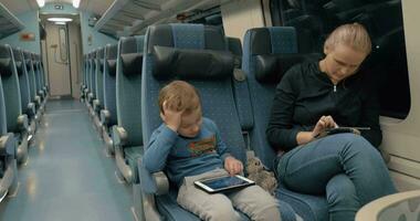 Family traveling by train and entertaining with electronics video