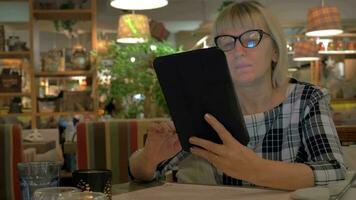 Senior woman browsing on touch pad in cafe video