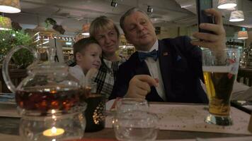 farföräldrar och barnbarn framställning selfie under familj middag i restaurang video