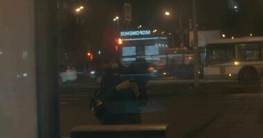 Woman with cell at bus stop in night city video