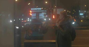 vrienden maken cel foto's wanneer aan het wachten voor de bus in nacht stad video