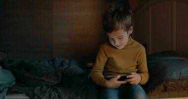 barn med mobiltelefon Sammanträde på säng på Hem video