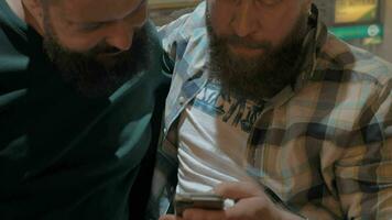 Close up view of two white mature bearded men using smartphone together video