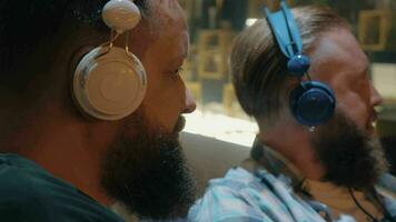 Close up view of two bearded men listening musics using colorful on-ear headset video