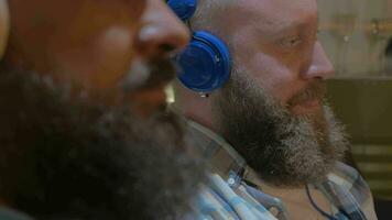 Close up view of two bearded men listening musics using colorful on-ear headset video