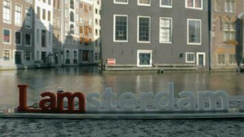 View of small plastic figure of Iamsterdam letters sculpture on the bridge against blurred cityscape, Amsterdam, Netherlands video