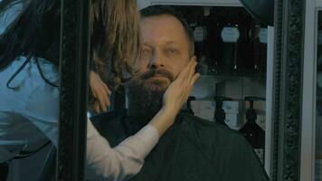 Close up view of female barber taking cares of lush beard of man Barber applying cosmetics video