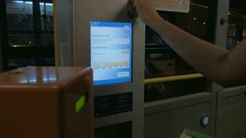 Woman using ticket machine to pay for bus ride video