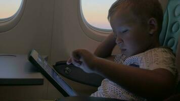 Close up view of small boy playing with touch pad on the table in aircraft video