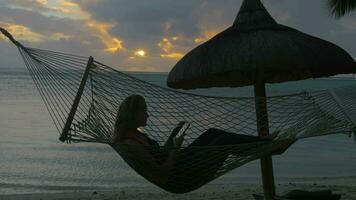 Frau entspannend im Hängematte auf Strand und nehmen Zelle Fotos video