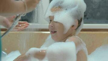 Mother washing foam from child in the bath video