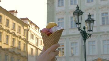 Aussicht von unkonzentriert Stadtbild auf das Hintergrund und dann gesehen Eis Sahne Bälle im das Waffel Tasse, Prag, Tschechisch Republik video