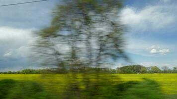 View from riding train window of coutryside landscape against cloudy sky video