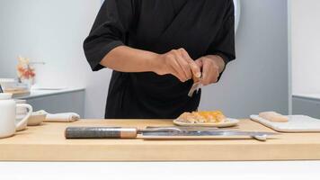 profesional cocinero preparando y Cocinando crudo Fresco pescado ingrediente en el mesa con cuchillo para delicioso Sushi y sashimi comida, persona haciendo lujo omakase multa comida japonés comida restaurante cena foto