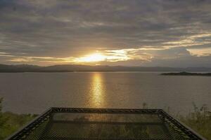 Travel for beautiful nature lake sunset with hammock, Relax vacation with landscape sky and evening sunlight, Calm outdoor holiday water reflection with cloud view background, peaceful calm horizon photo