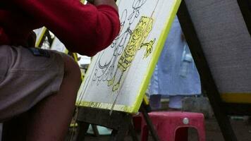 Magelang, Indonesia.09-16-2023.a child is coloring with watercolors a spong bob painting. video