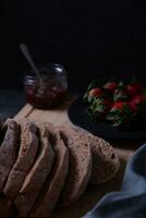 Freshly prepared and sliced bread served on the table with jam and strawberries. photo