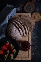 Freshly prepared and sliced bread served on the table with jam and strawberries. photo