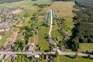 panoramic aerial view of eco village with wooden houses, gravel road, gardens and orchards photo