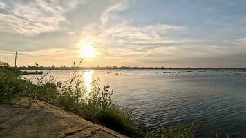 rivieroever zonsondergang video, rivier- visie Bij zonsondergang, boot drijvend Aan de rivier- Bij zonsondergang, middag video van zonsondergang Aan de rivier-