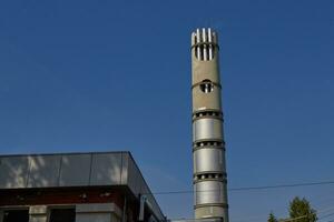 Photo of metal chimney against blue sky.