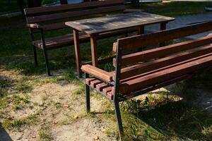 Photo of bench with wooden table outside. Place