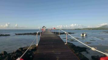 Aerial view of coast line of Mauritius Island, water laves, camera moves along pear in sea against sky video