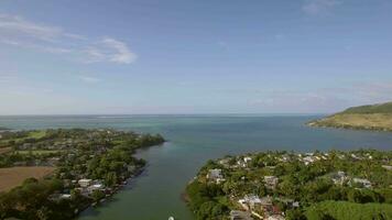 Coastal town and river falling into ocean Mauritius aerial view video