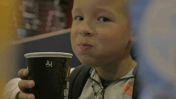 View of small boy drinking from the paper cup and smiling, fast food cafe video