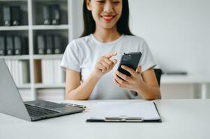 Asian Woman using smart phone for mobile payments online shopping, omni channel, sitting on table, virtual icons graphics interface screen photo