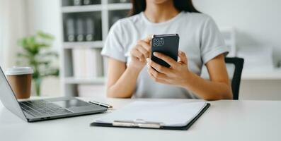 Asian Woman using smart phone for mobile payments online shopping, omni channel, sitting on table, virtual icons graphics interface screen photo