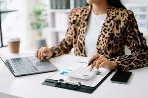 Close up of businesswoman or accountant hand typing laptop working to calculate on desk about cost at home office. photo