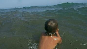 Child with ball swimming in wavy sea video